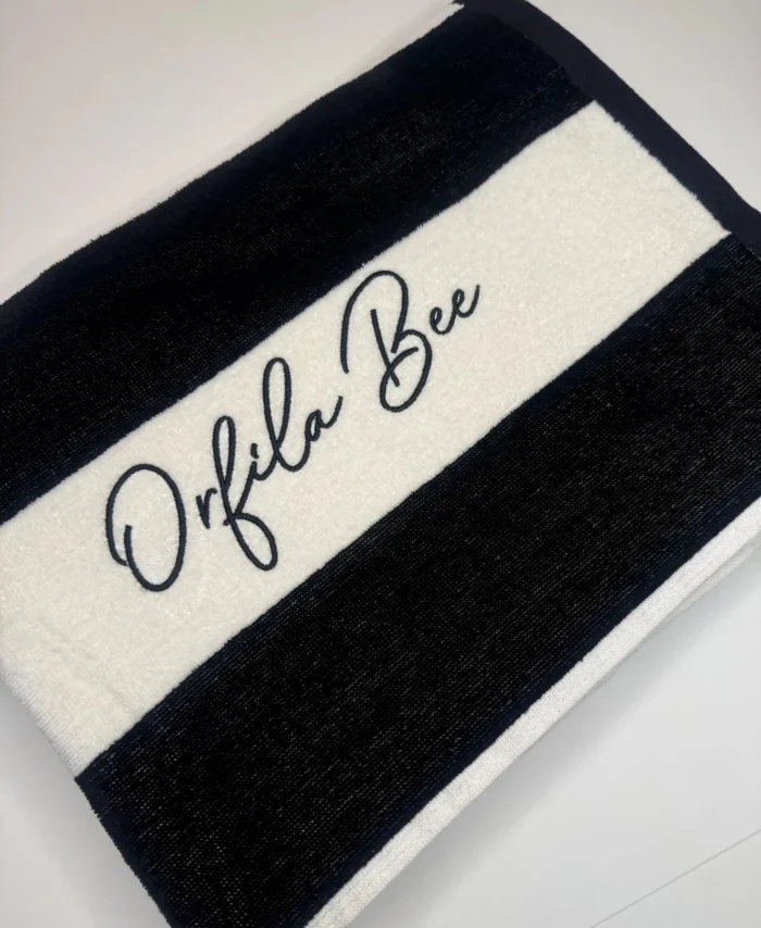 Black and white striped personalised beach towel with elegant script name embroidery in black thread, luxury cotton custom pool and holiday towel gift.