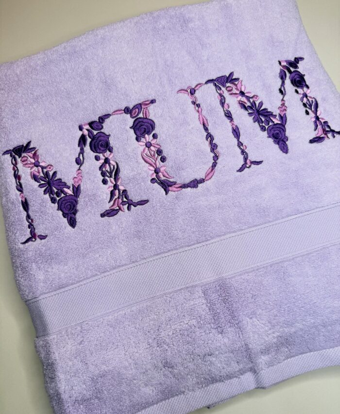 Luxury lavender bath towel embroidered with the word “Mum” in purple floral lettering, personalised embroidered gift for Mother’s Day or birthday in the UK.