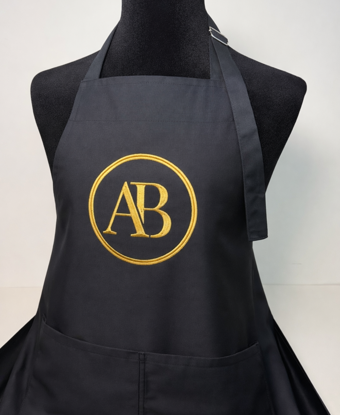 personalised black apron with gold embroidered AB logo, premium custom workwear with front pockets