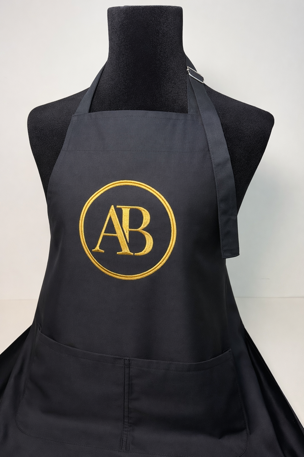 personalised black apron with gold embroidered AB logo, premium custom workwear with front pockets