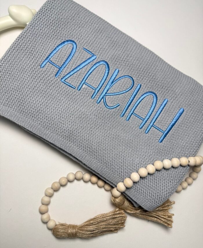 Grey personalised knitted baby blanket embroidered with baby name in blue thread